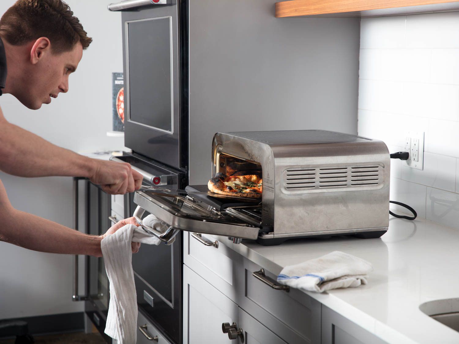 Taking a finished pizza out of the Breville oven.