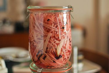 Two stacked Weck canning jars filled with shredded kohlrabi quick pickle.