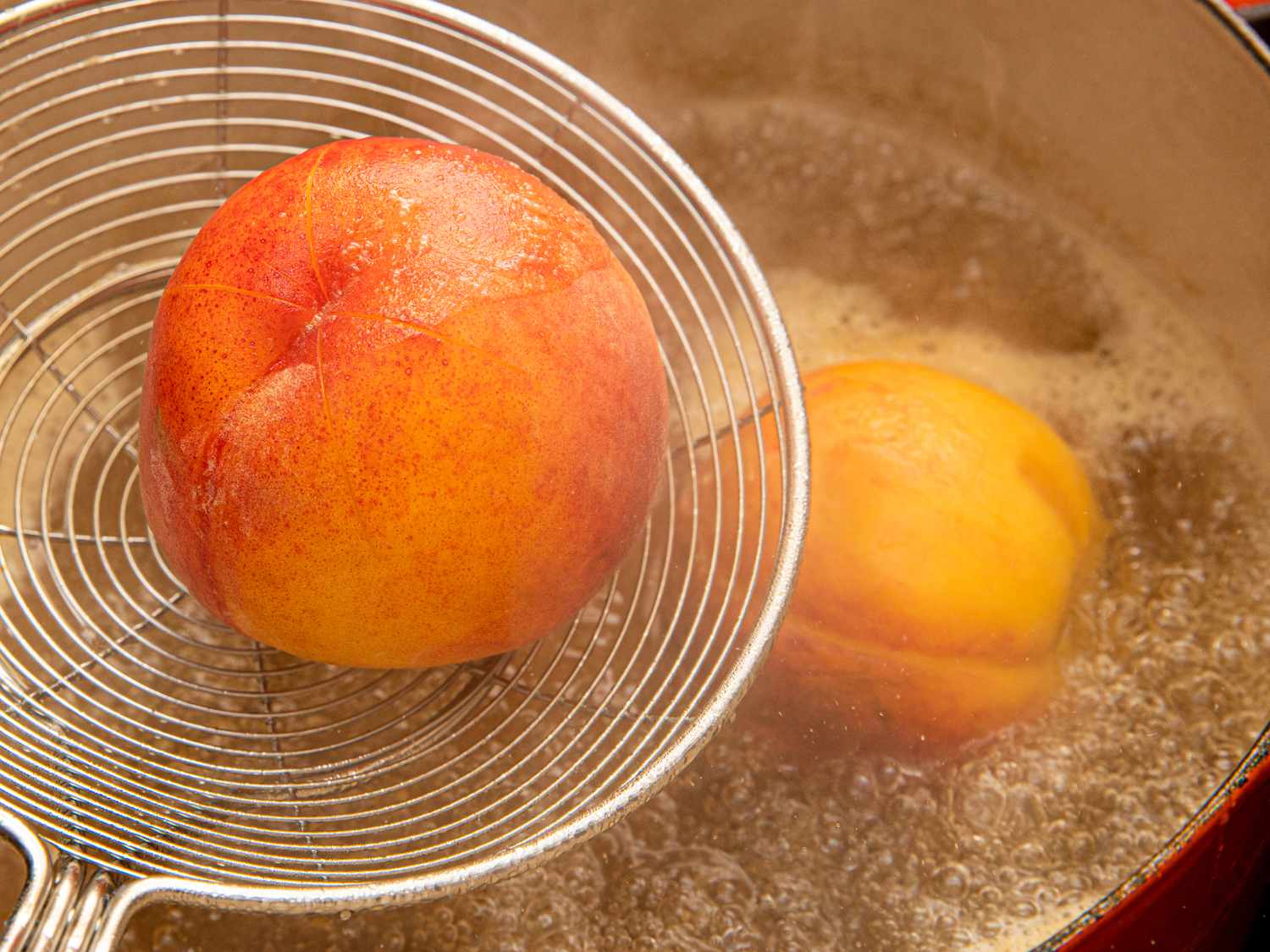 Overhead of lower peach into boiling sauce