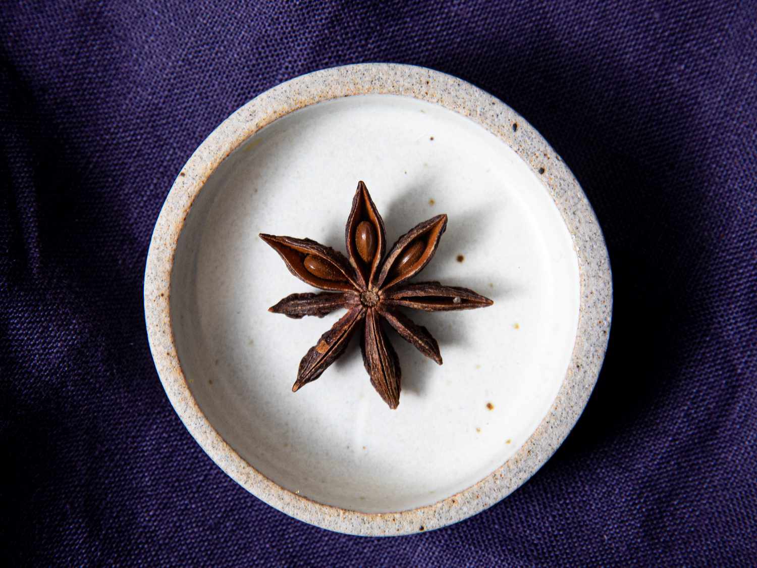 Overhead view of. a single star anise pod in a small bowl