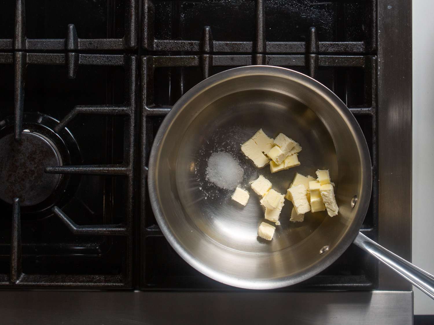 Overhead view of a saucier with the cubed butter, water, and salt, ready to heat.