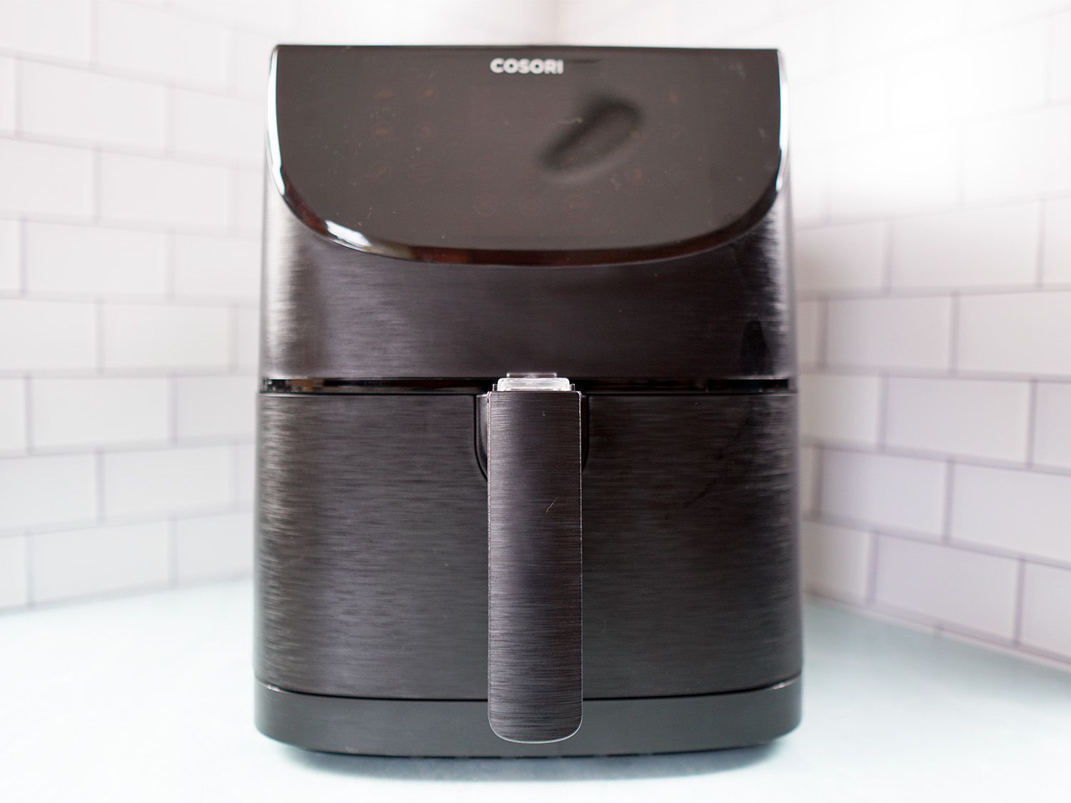 a black air fryer sitting on a blue surface