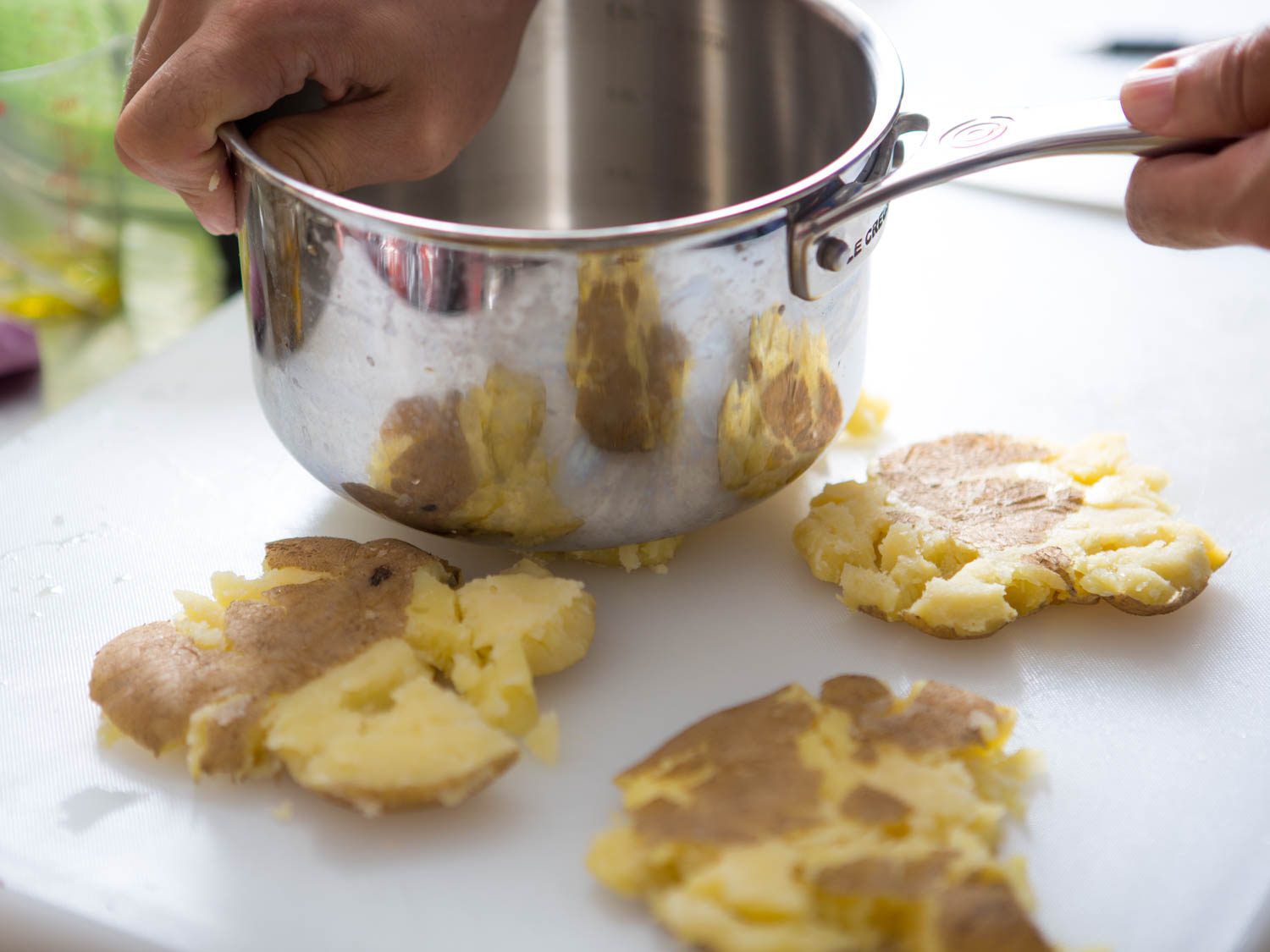 Smashing boiled potatoes with the bottom of a small pot.