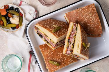 Sliced muffuletta sandwich in an enameled metal tray.