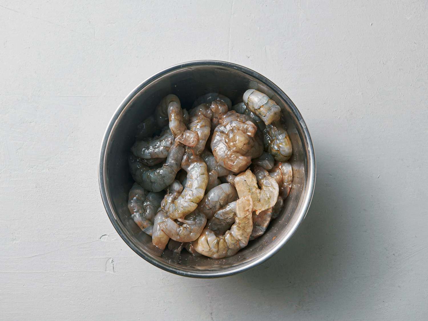 Peeled shrimp, salt, and baking soda stirred inside a medium bowl