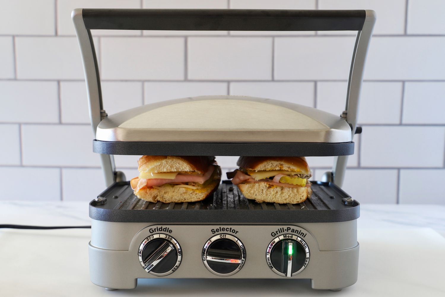 A panini press pressing two sandwiches on medium heat