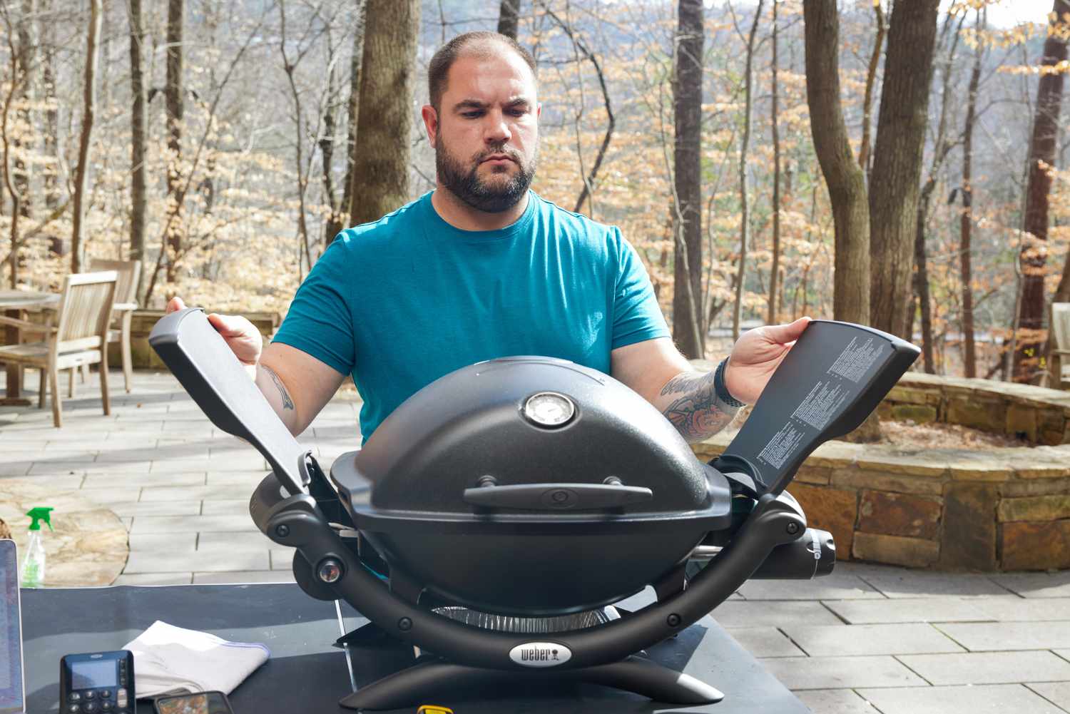 a person closing the wings of a portable gas grill