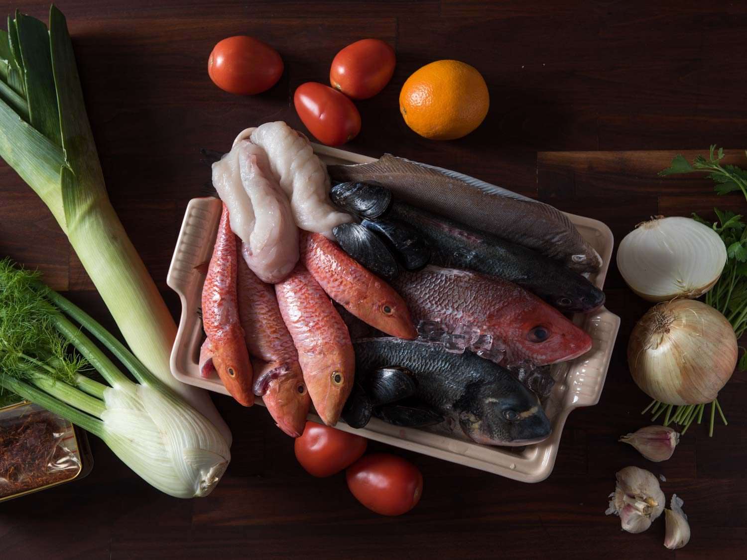 The ingredients used for bouillabaisse: mixed fish, fennel, onion, garlic, tomato, orange, saffron, and more.