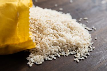 Carolina Gold rice spilling out onto a wooden counter from a paper bag.