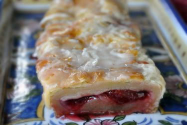 A close-up of a sliced kringle with cherry jam.