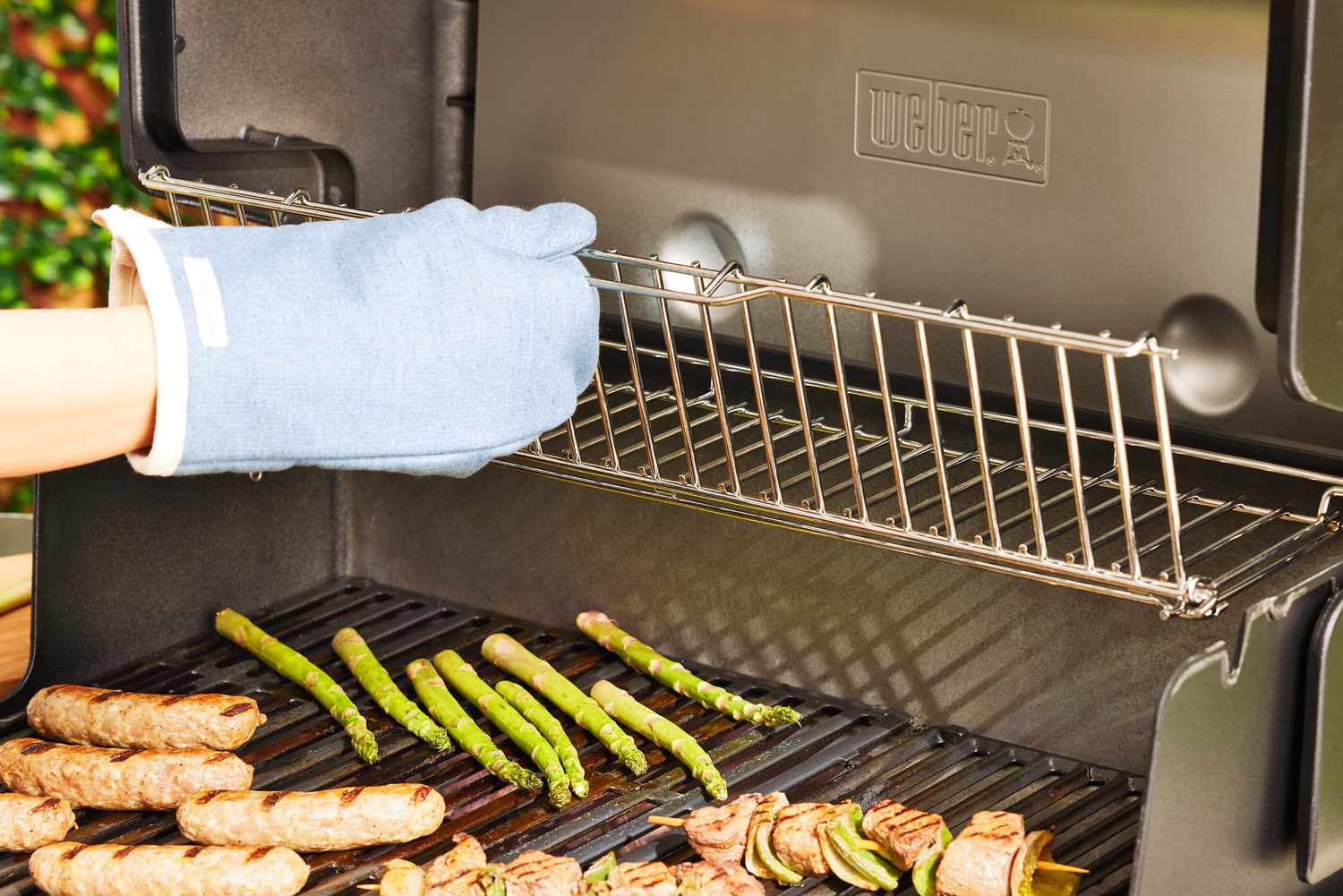 Skewers, sausages, and asparagus cooking on a Weber gas grill