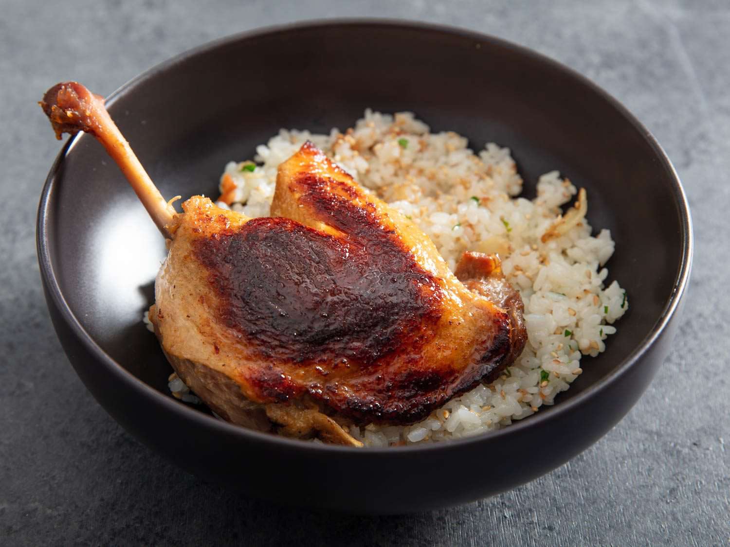 一个碗的特写与酥脆的腿曲鸭装在米饭上。