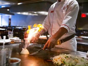 A Benihana chef making an onion volcano on the grill.