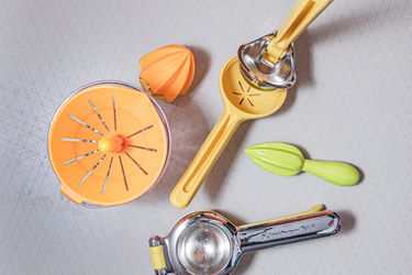 four different styles of citrus juicers on a white surface