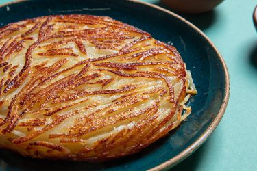 盘子里放着一个金黄色的土豆煎饼。它是圆的，厚的，由清晰的马铃薯丝组成。
