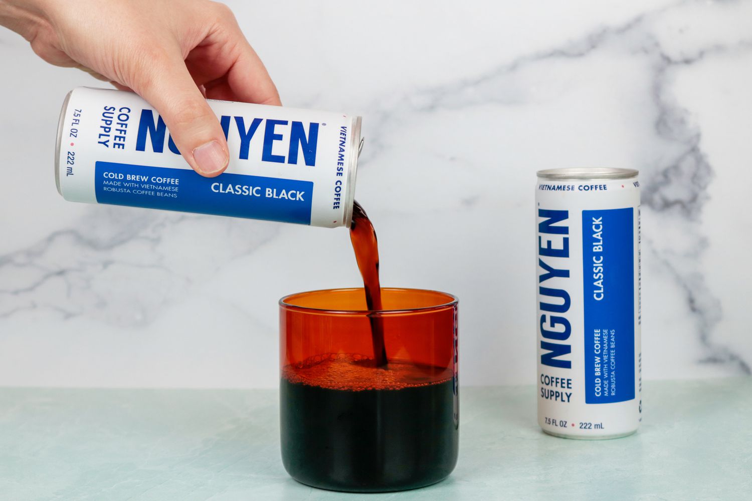 A hand pouring a can of coffee into a mug