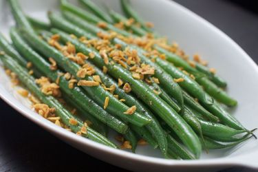 A plate of cryo-blanched green beans topped with crunchy fried garlic.