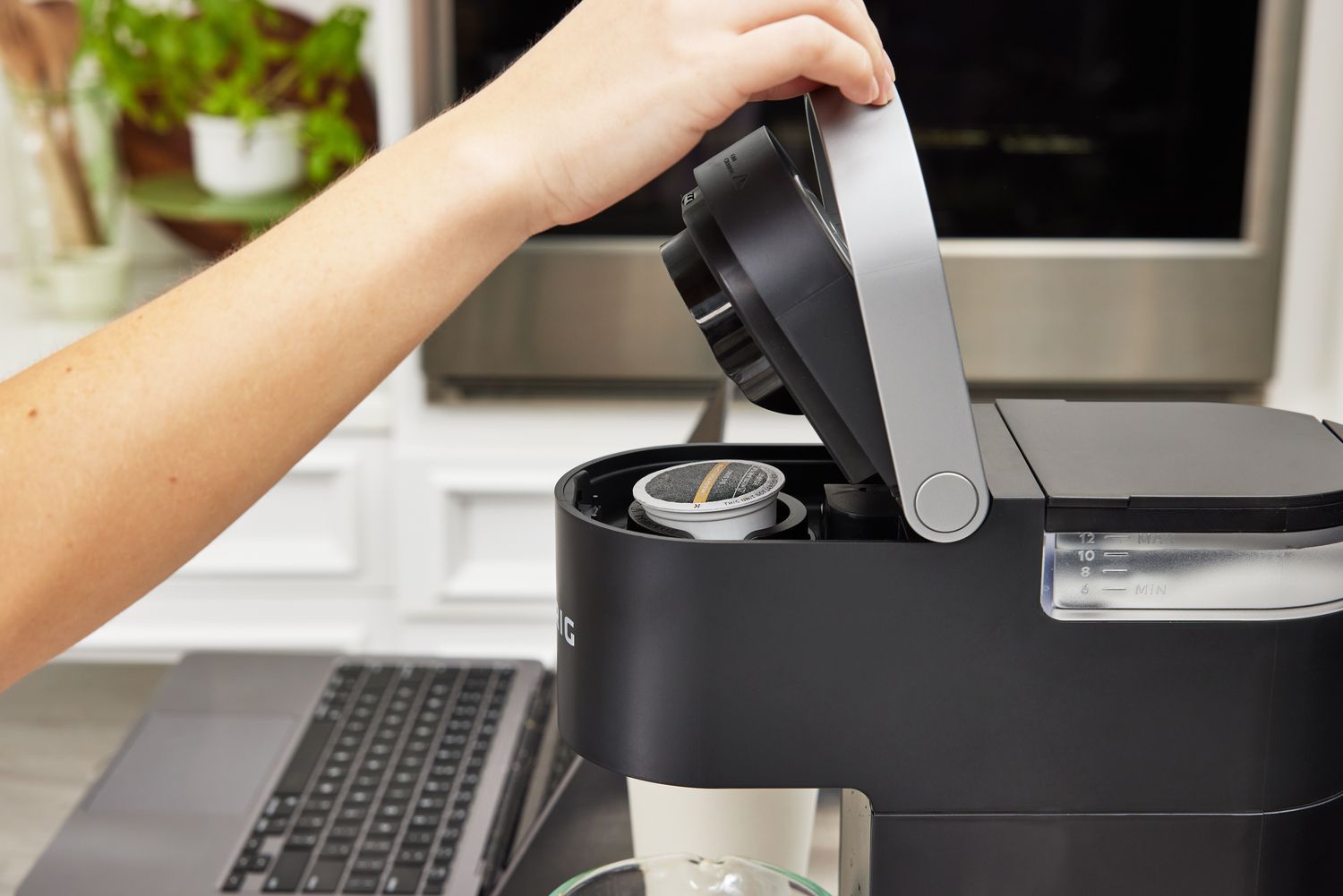 一个hand closing the lid of a keurig machine