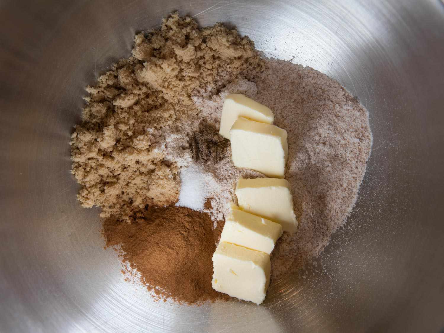 Whole wheat flour, brown sugar, salt, spices, and pieces of butter in a mixer bowl.