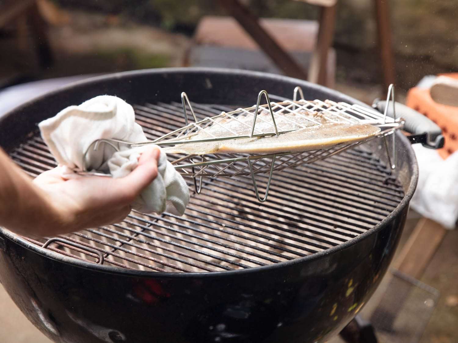 在烤架上翻动大比目鱼，用毛巾抓住巴斯克鱼烤架。