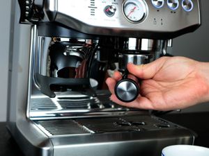 a hand inserts a portafilter into an espresso machine