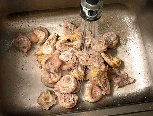 在一个巨大的不锈钢水槽里清洗焯过的猪肉和鸡骨。