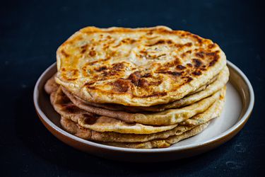 A stack of aloo paratha with spiced potato filling on a plate.