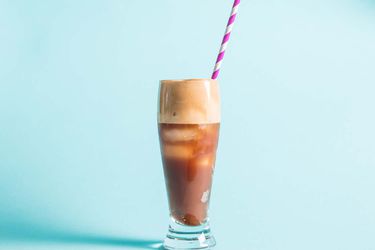 Profile view of frappé served in a tall pilsner glass with a candy cane-striped straw.