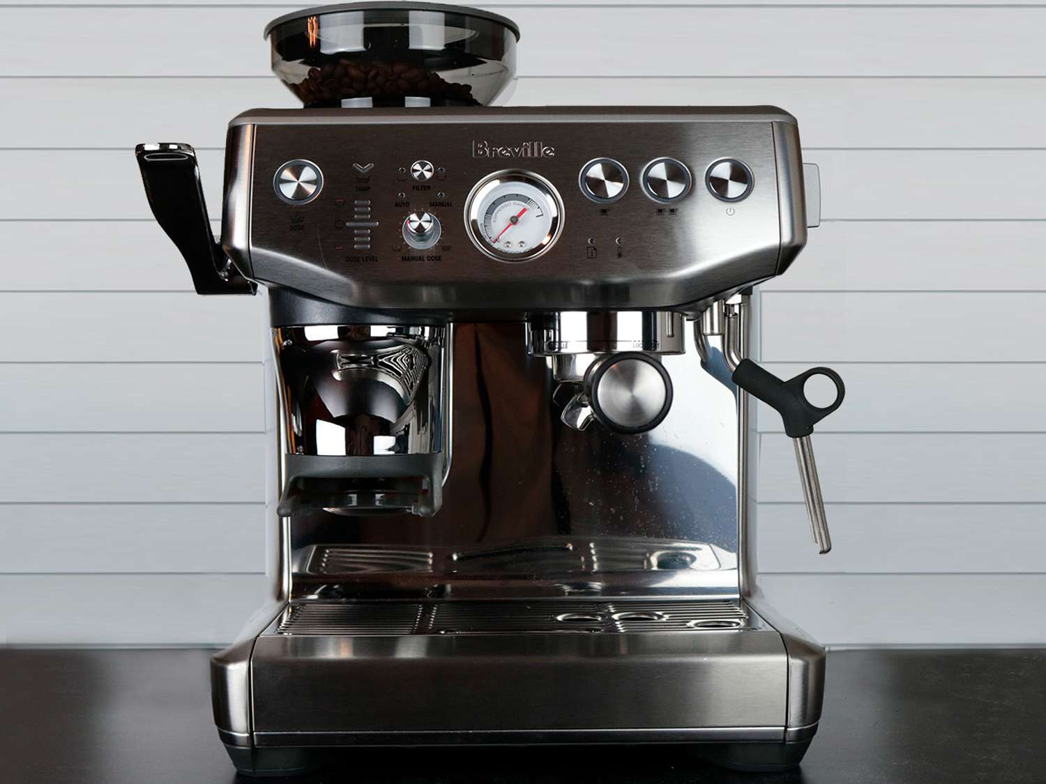 an espresso machine with a built-in grinder sits on a counter in front of a tiled wall