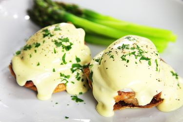 two eggs benedict plated with asparagus