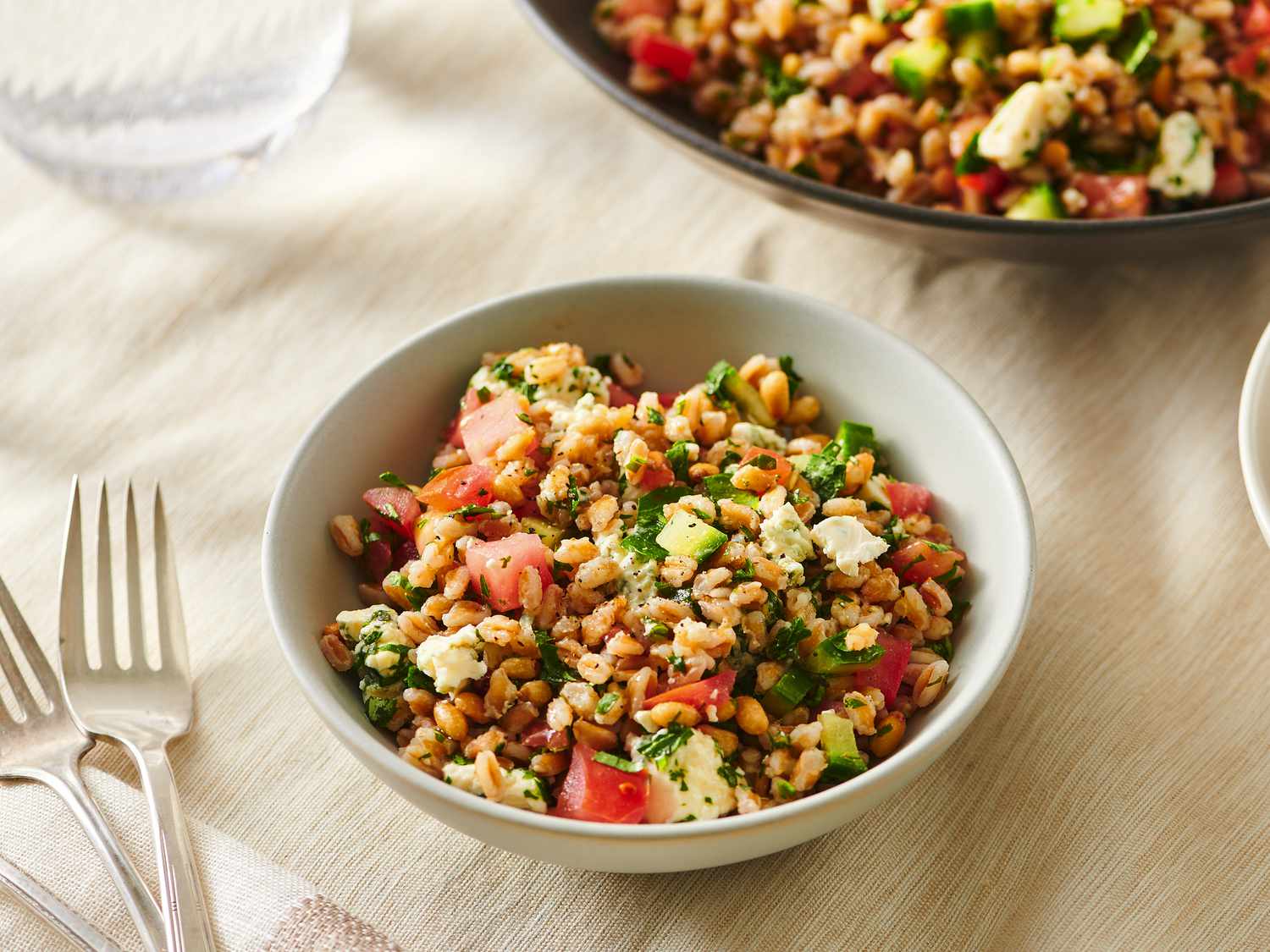 Serving of farro salad with blue cheese, pine nuts, and tomatoes served inside a bowl