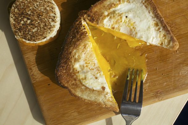 烤芝士蛋爆三明治(在两片烤芝士用的面包上打个洞，把鸡蛋煮熟)，切成块，蛋黄洒出来，放在木砧板上