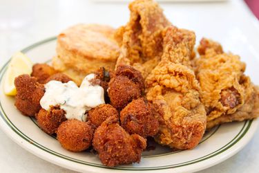 A plate of hushpuppies and chicken and a biscuit