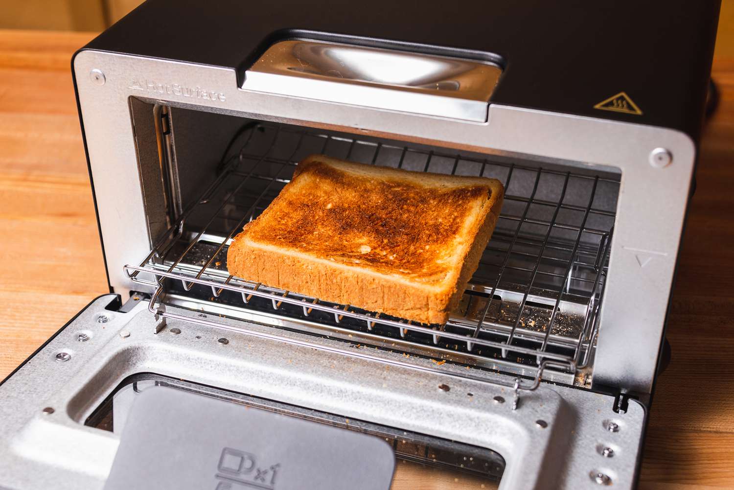 A piece of toast in the Balmuda toaster with the toaster oven's door open