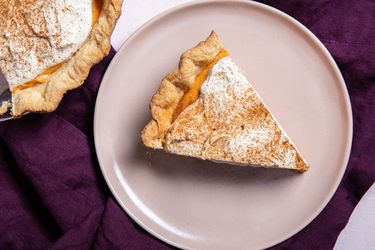 Slice of pumpkin chiffon pie on a serving plate next to pie plate with pumpkin chiffon pie