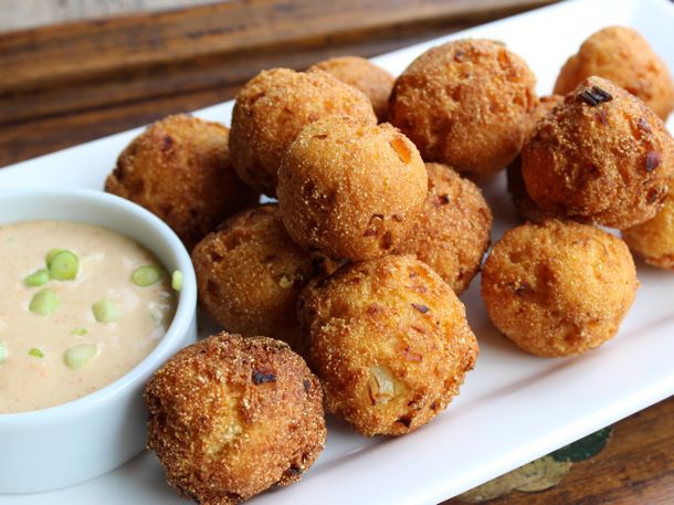 A plate of hushpuppies next to some dipping sauce.