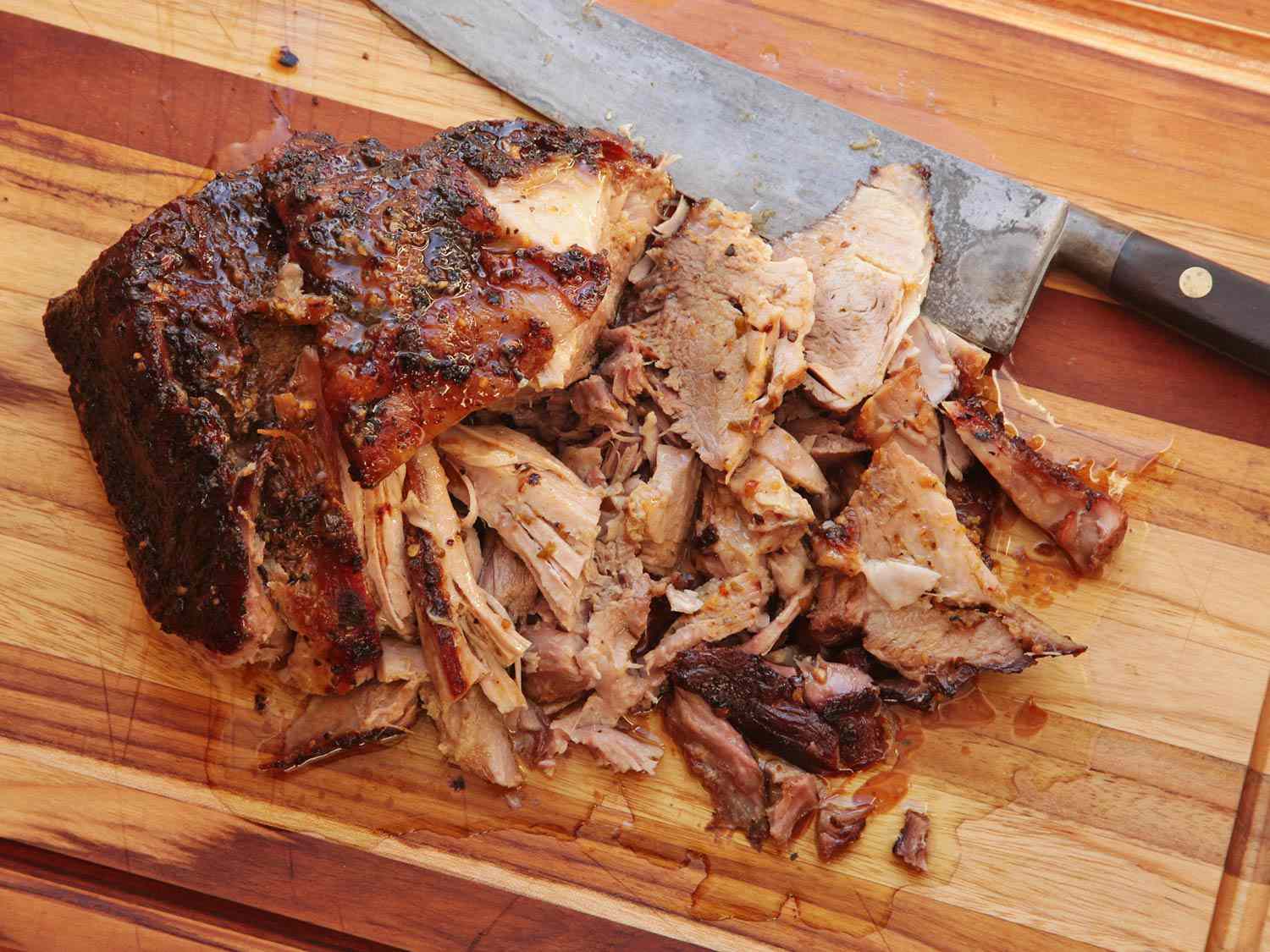 Cooked Cuban roast pork cut and pulled apart on a cutting board.