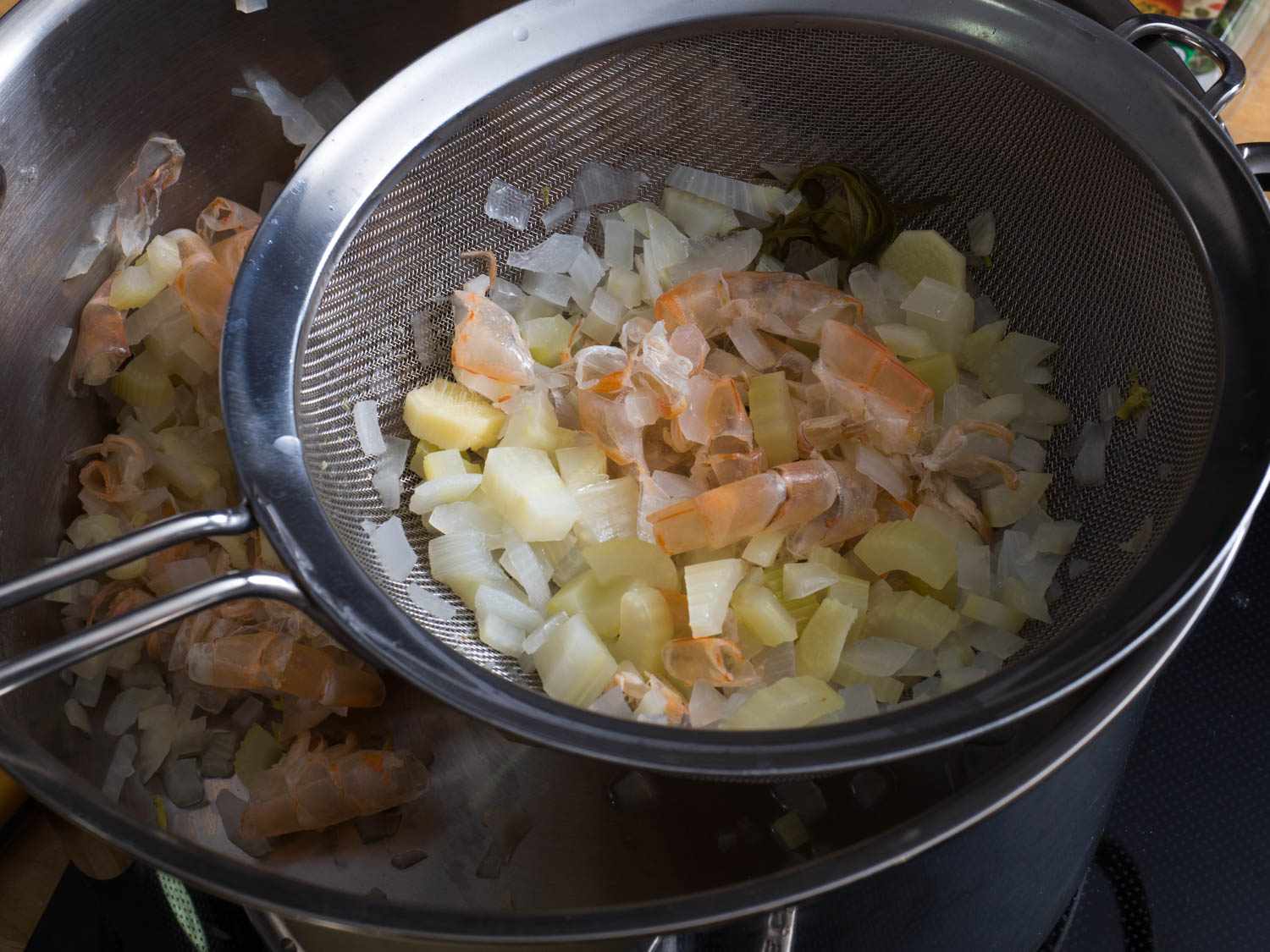 虾壳和肉汤中的其他固体用一个小过滤器从锅中除去。gydF4y2Ba