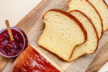 俯视of sliced brioche loaf on a cutting board next to jam