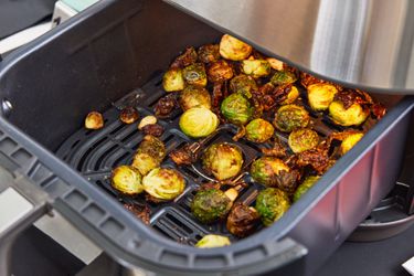 a closeup look at crispy Brussels sprouts in an air fryer basket