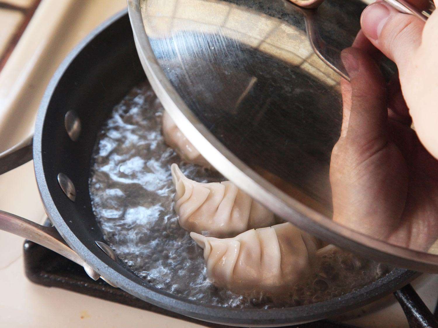 在不粘锅上盖上锅盖，让饺子蒸熟。