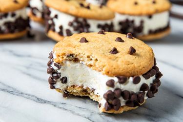 Ice cream sandwiches made with chocolate chip cookies and vanilla ice cream, with mini-chocolate chips rolled on the sides.