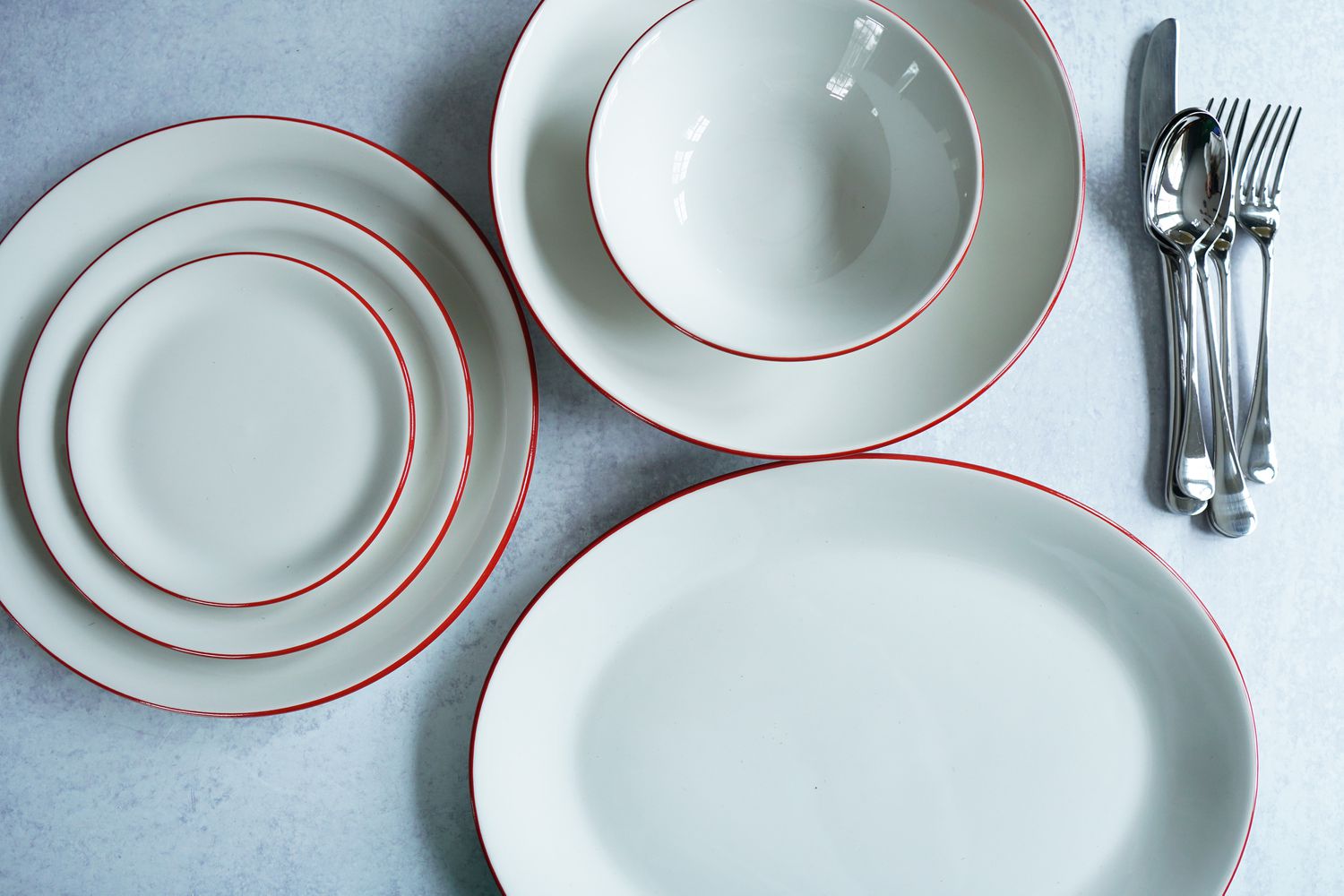 a place setting, serving platter, and silverware on a grey surface