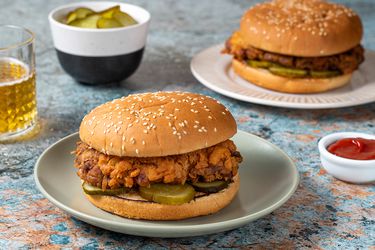 Two fried chicken sandwiches on ceramic plates.