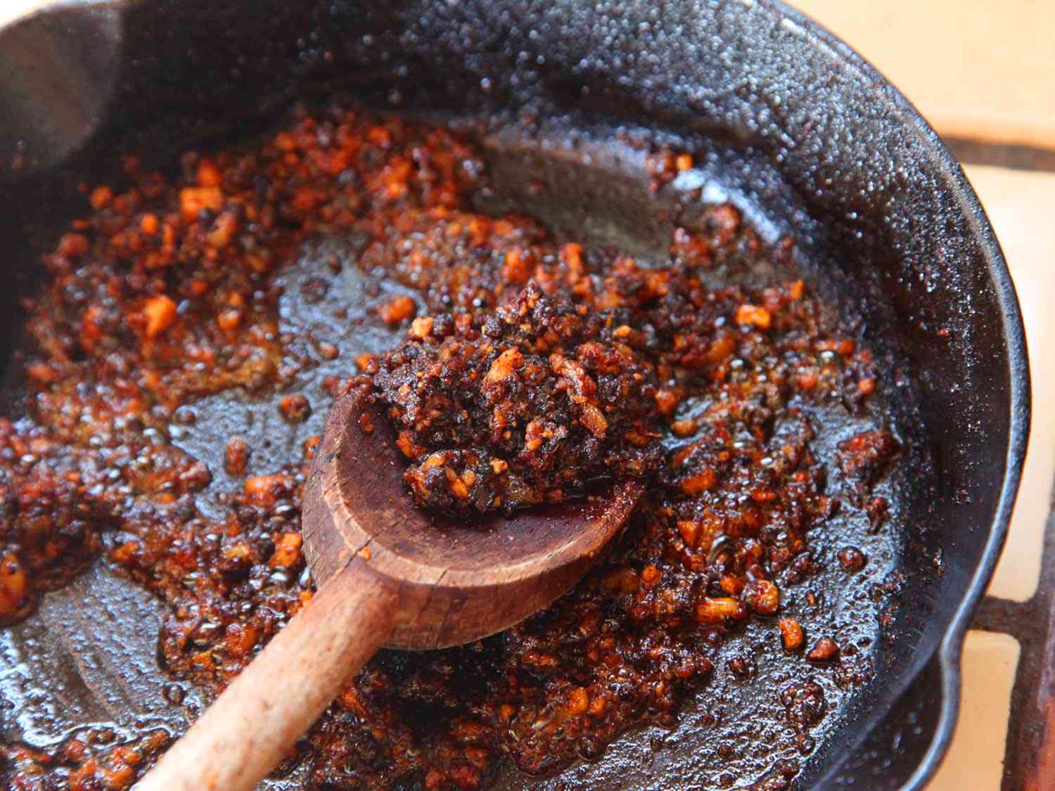 在铸铁煎锅中烹饪素食香肠的特写，用木勺搅拌。