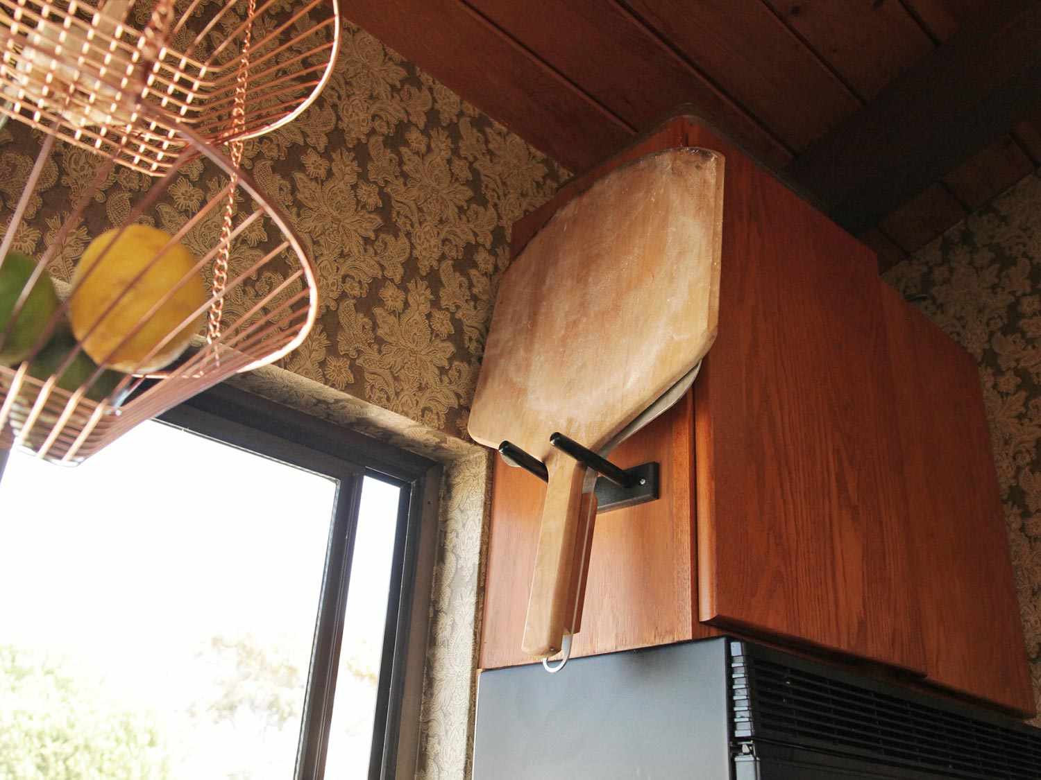 厨房橱柜旁挂着木制和金属的披萨皮