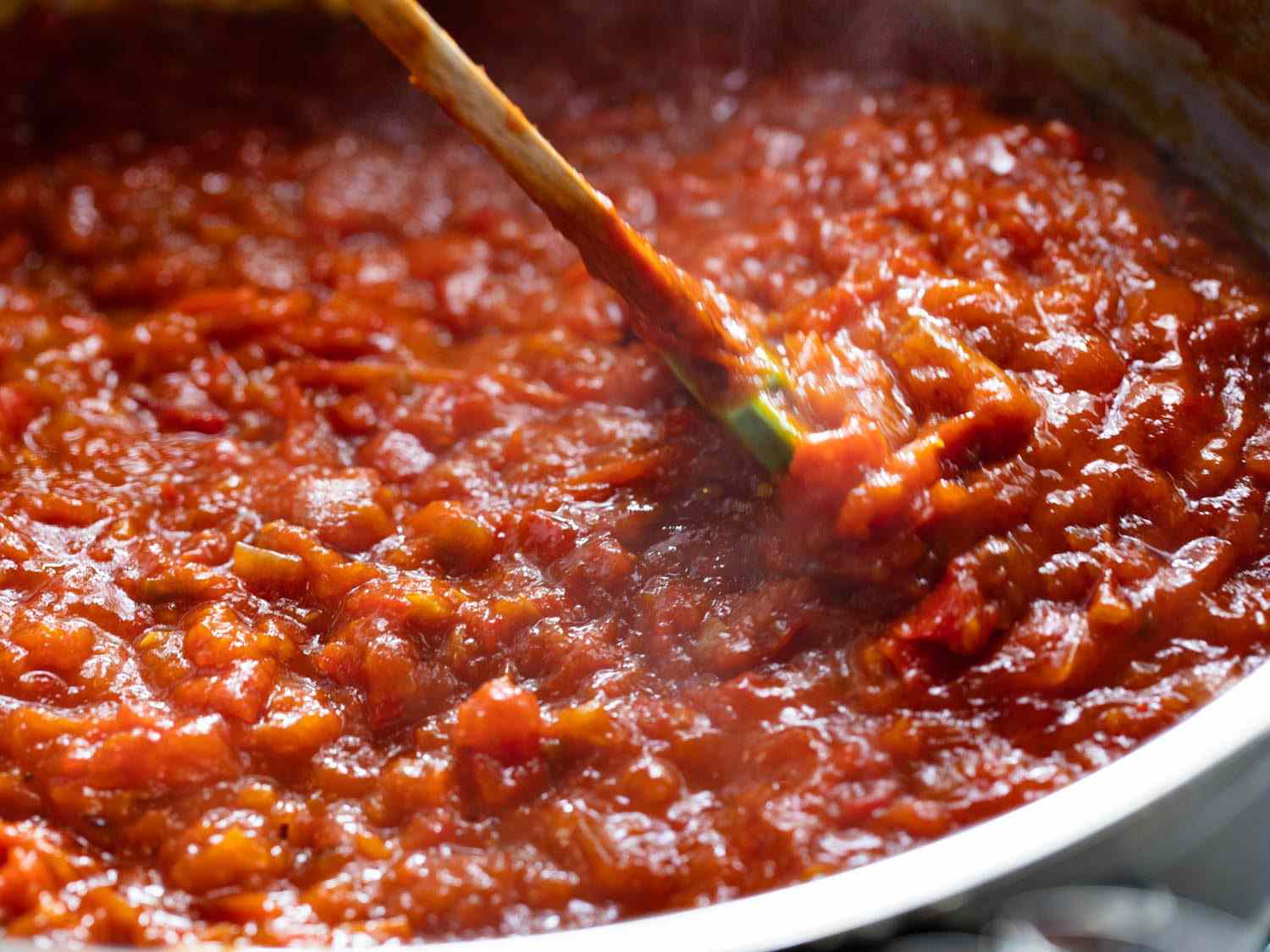 A pot full of simmering obe ata as a spoon stirs it.