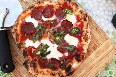 Overhead shot of Neapolitan-style pizza with spicy salami, mozzarella, chiles, and honey
