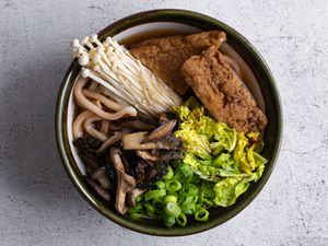 日本乌冬面用陶瓷碗盛着蘑菇酱油汤、炒蘑菇、生蘑菇、葱丝、卷心菜和豆腐。