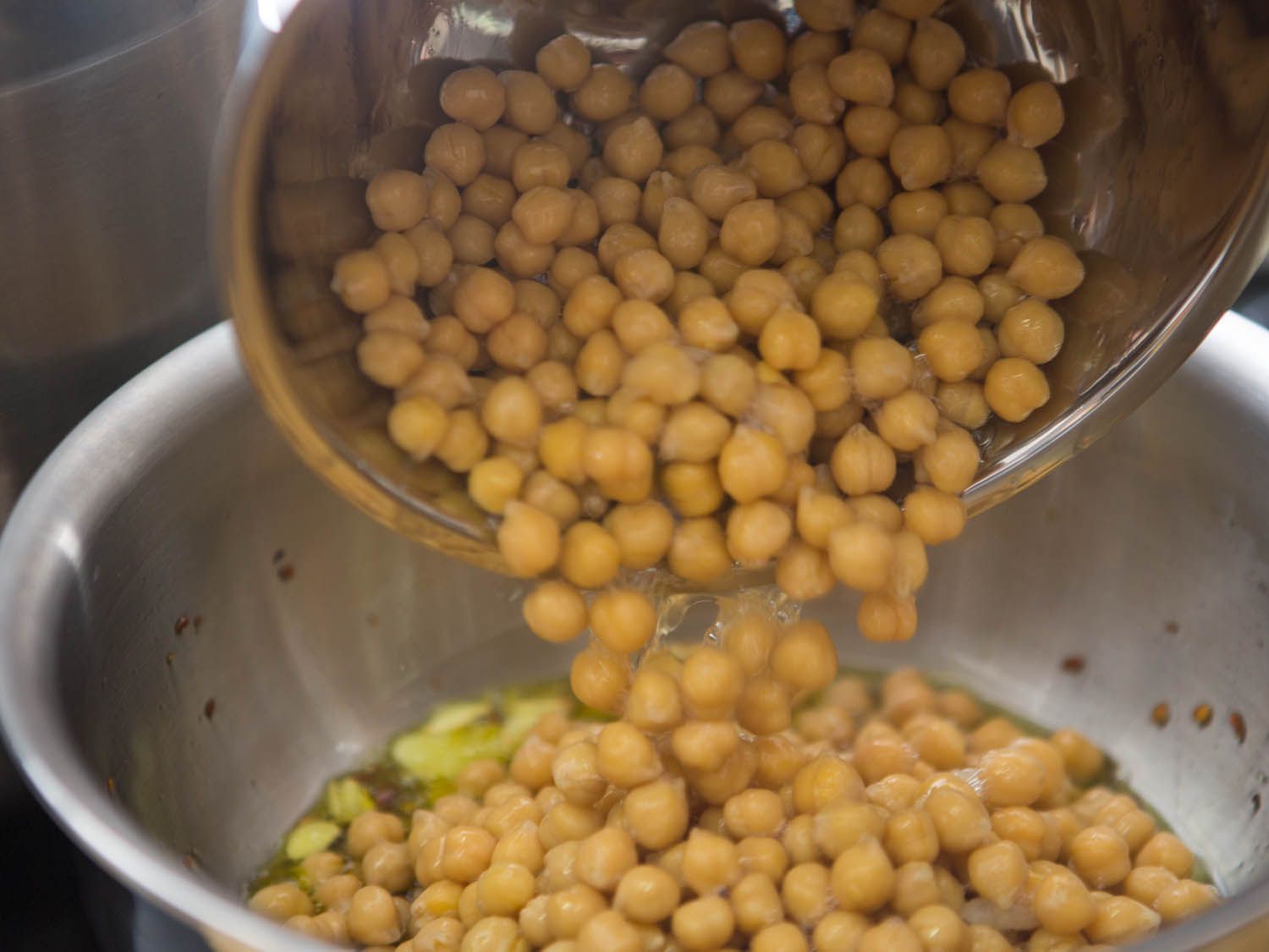 将沥干的鹰嘴豆倒入碗中，加入大蒜片和碎红辣椒片。